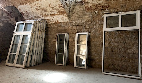 Die alten Aluminiumfenster werden zwischengelagert, bis sie für das geplante Gewächshaus Verwendung finden.
